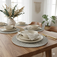 Dining table set with white ceramic plates, bowls, and gold cutlery on white wash woven rattan placemats.