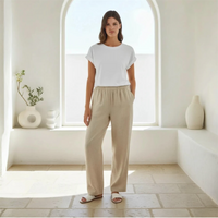Woman wearing a white t-shirt and beige pants standing in a bright, minimalistic room.