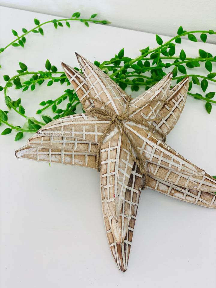 Decorative starfish with a checkered pattern on a white background with green leaves.