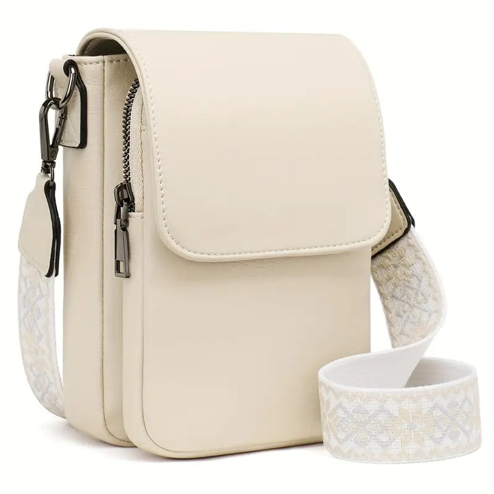 Beige foldover crossbody bag with front zip pocket and patterned adjustable strap