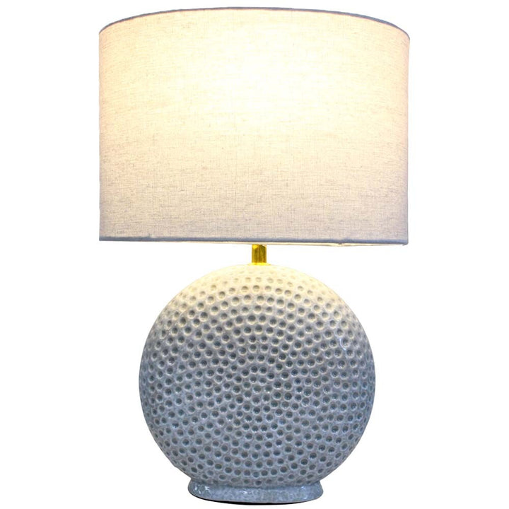 Table lamp with textured ceramic base and white lampshade on a white background