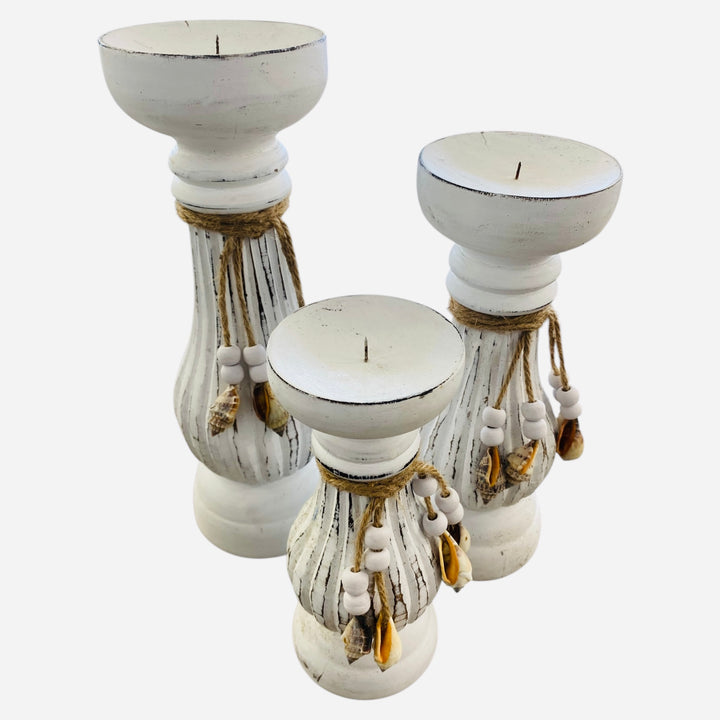 Set of three white  pillar candle holders with decorative elements on a white background