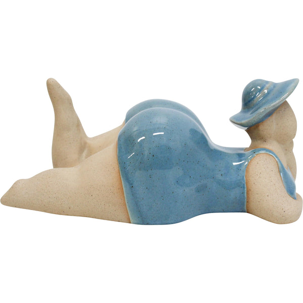 Ceramic figurine of a woman in a blue swimsuit and hat on a white background sunbathing at the beach