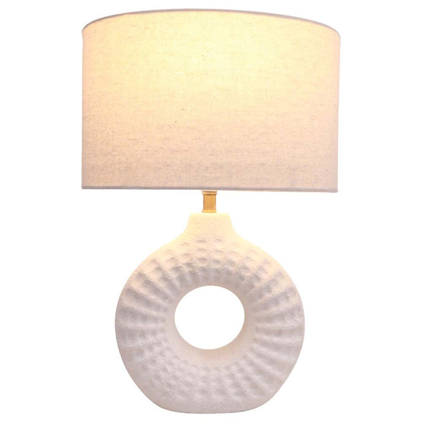Table lamp with a textured white base and beige fabric shade on a white background