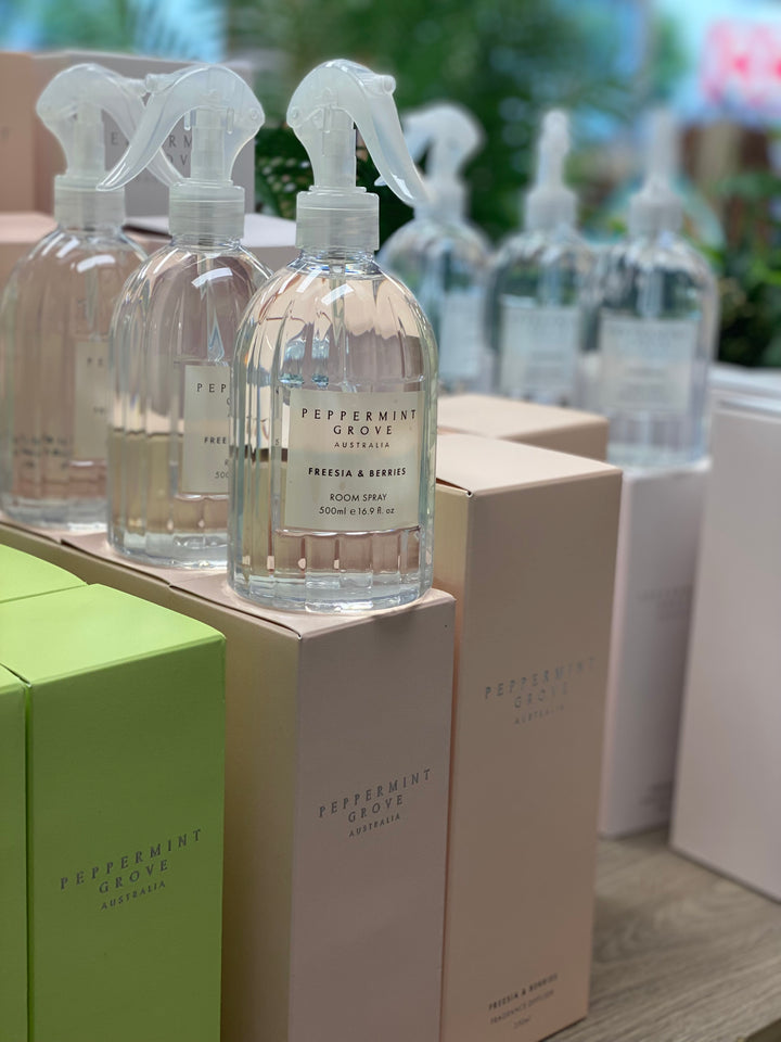 Row of Peppermint Grove room spray bottles on a wooden surface with boxes.