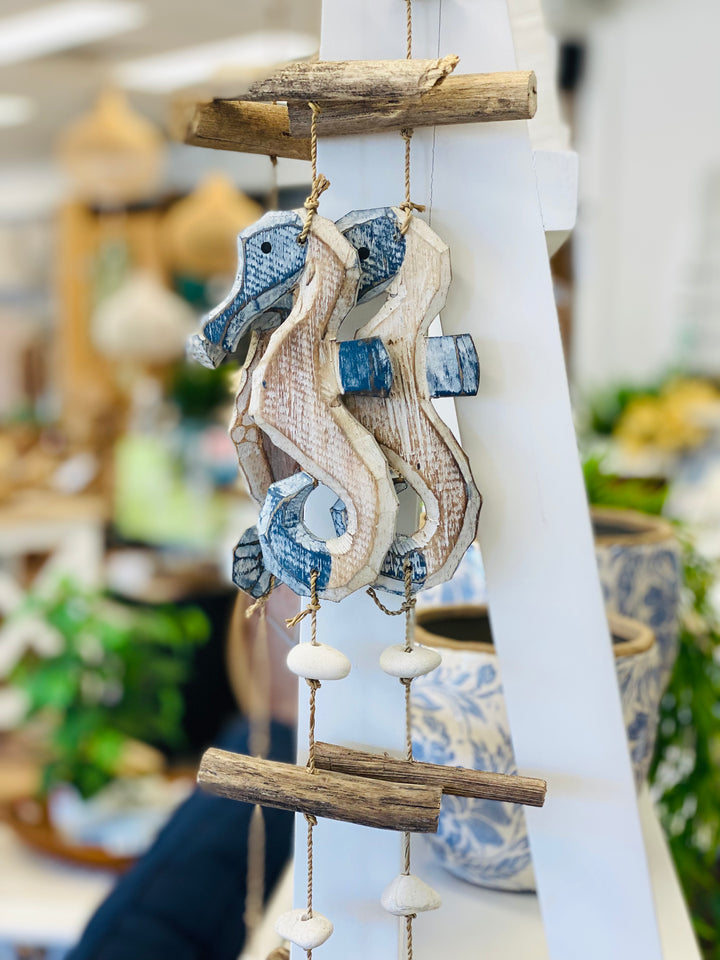 Decorative seahorse ornament with blue accents hanging on a white surface.