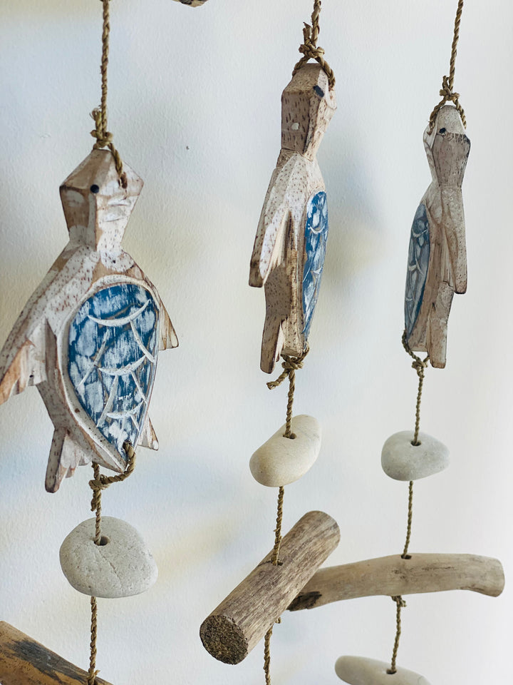 Decorative hanging mobile with stone pieces and driftwood on a white background