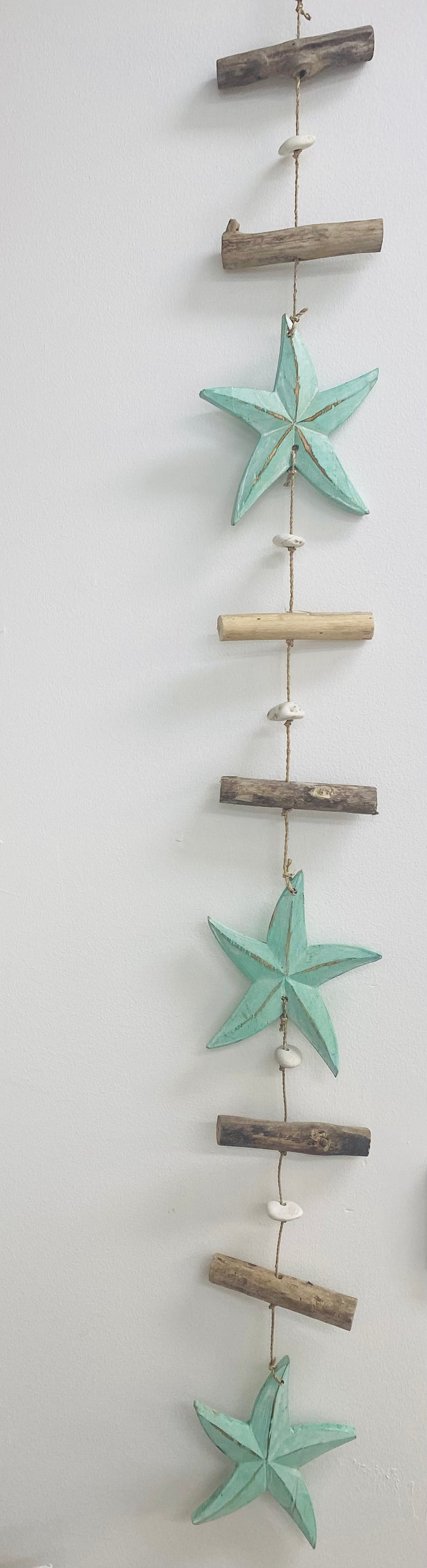 Decorative wall hanging with starfish and driftwood on a white background