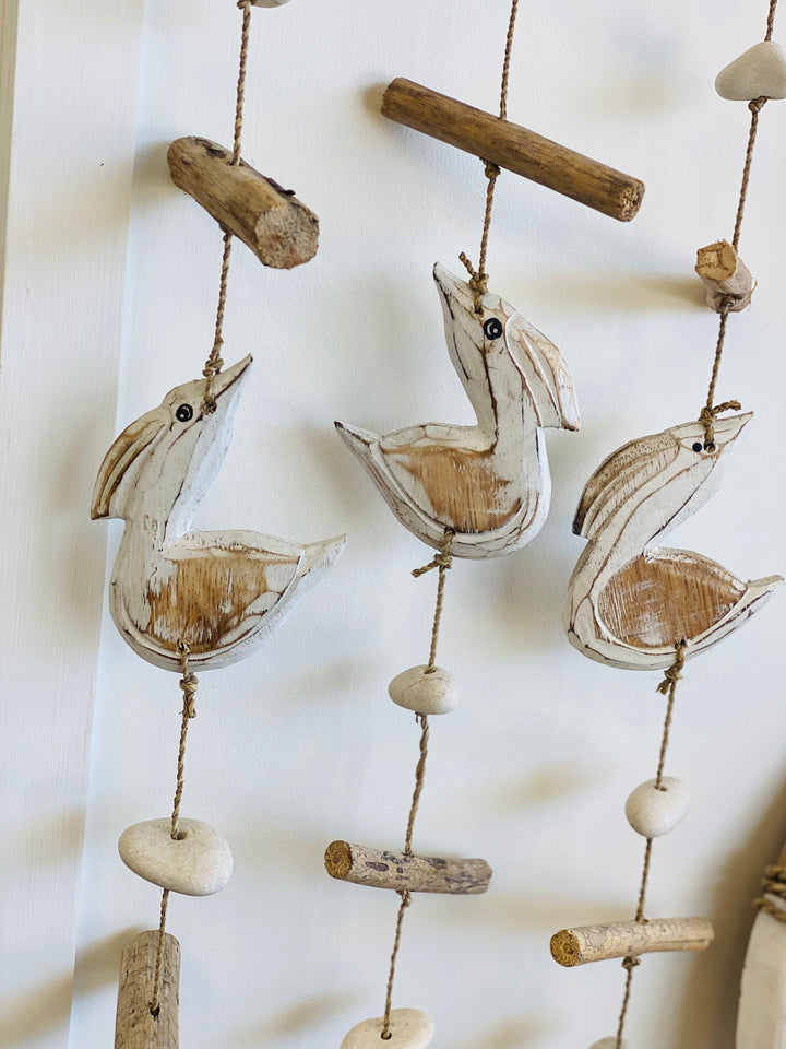 Decorative hanging with wooden pelicans and stones on a white background
