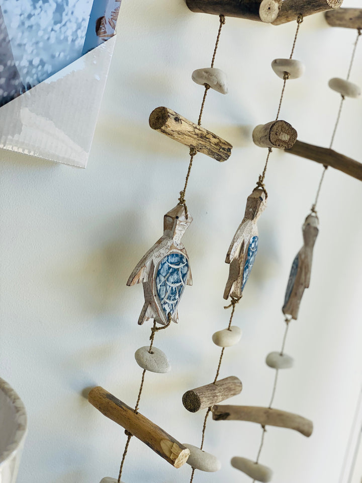 Decorative mobile with turtle figures and driftwood on a white background