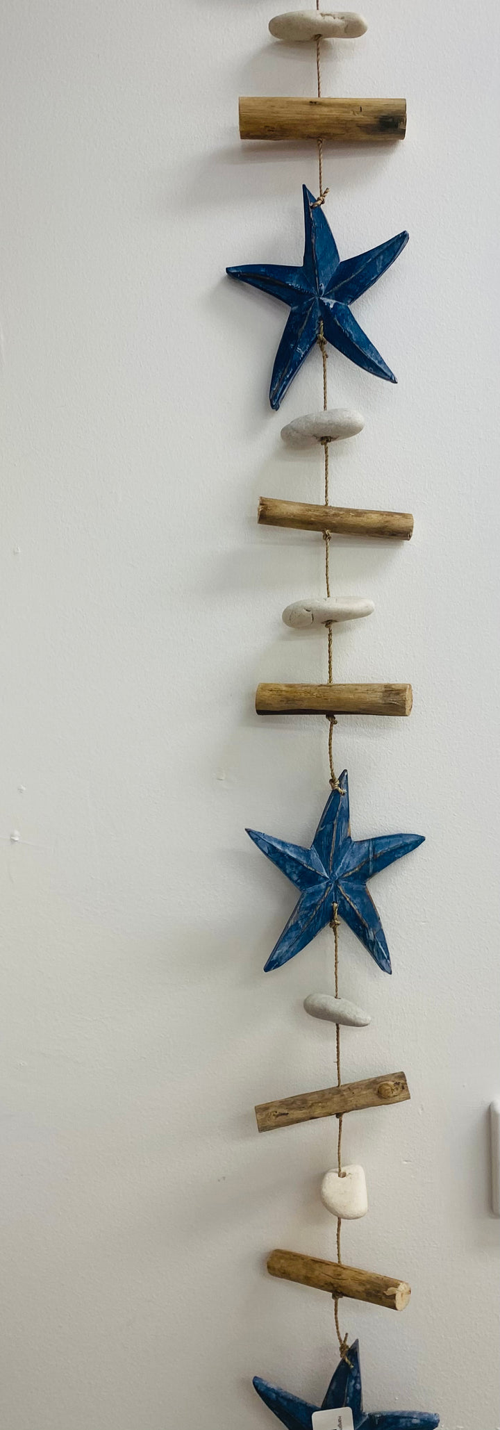 Decorative wall hanging with navy starfish and wooden sticks on a white background