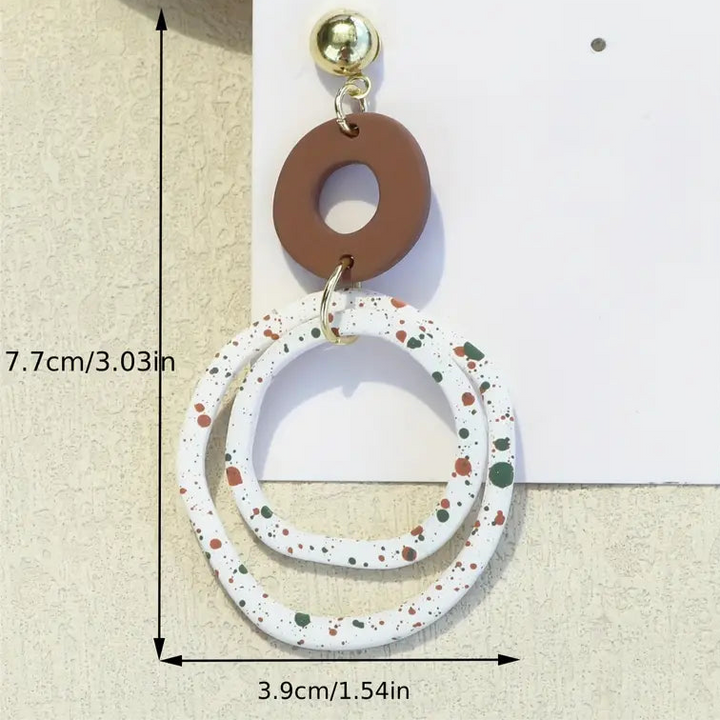 Pair of earrings with circular designs on a beige background with measurements.