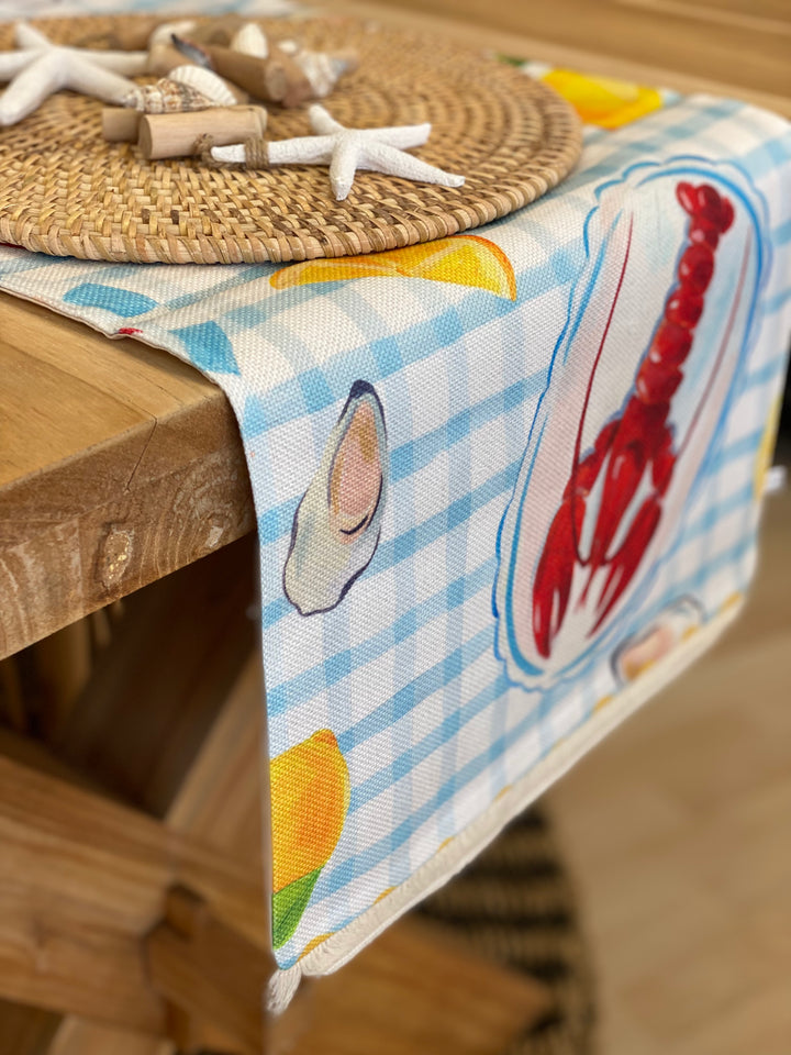 Lobster coastal table runner with red lobster, oysters and lemon print on blue and white checked background, perfect for summer or seaside dining