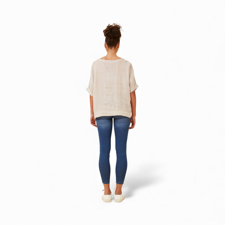 woman wearing a natural coloured linen top and blue jeans on a white background