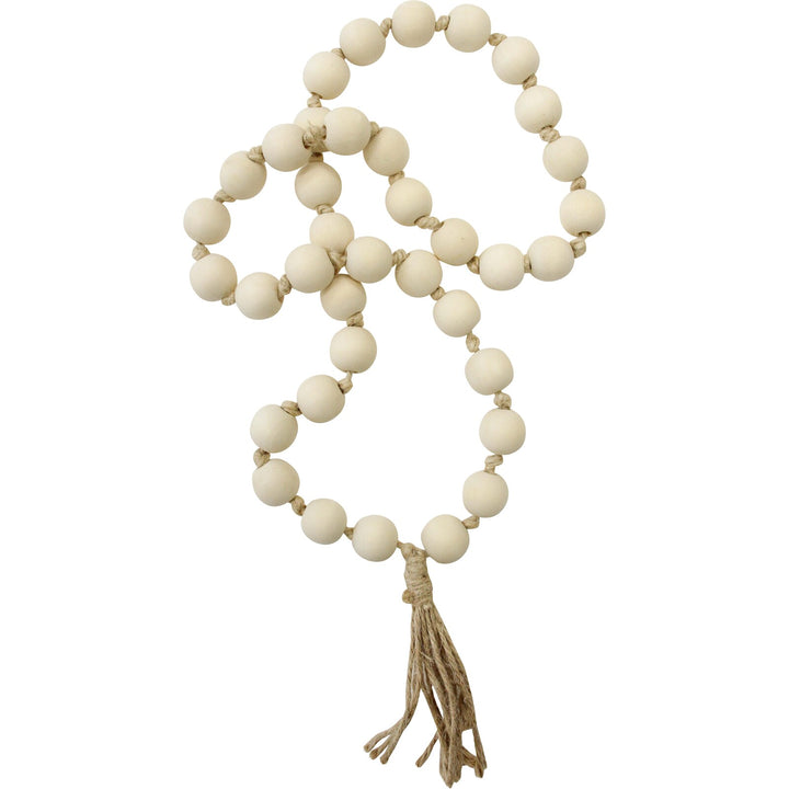 A neutral-colored string of tassel loop beads with a soft-toned tassel, styled as minimalist home decor for a calm, earthy aesthetic.