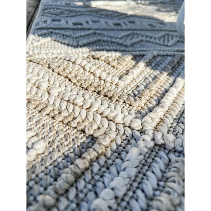 Close-up of a textured blue and beige area rug with geometric pattern.