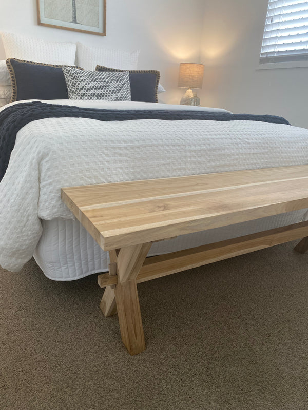 teak timber bench seat placed at the end of a bed