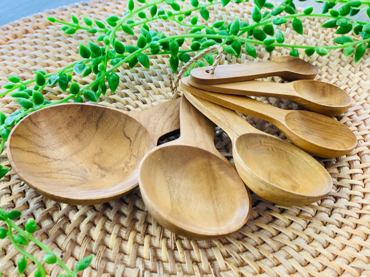Set of wooden spoons on a woven mat with greenery