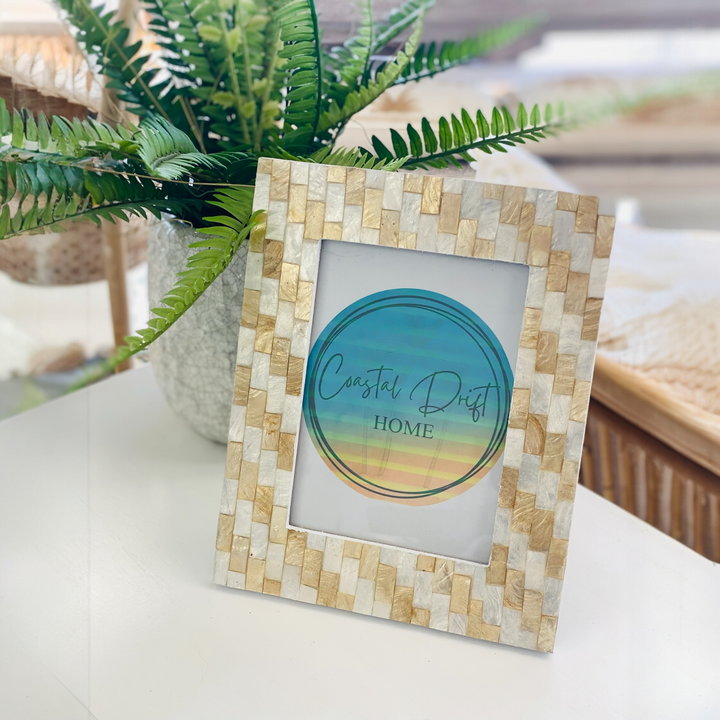 Decorative picture frame with mosaic design on a table with a plant in the background
