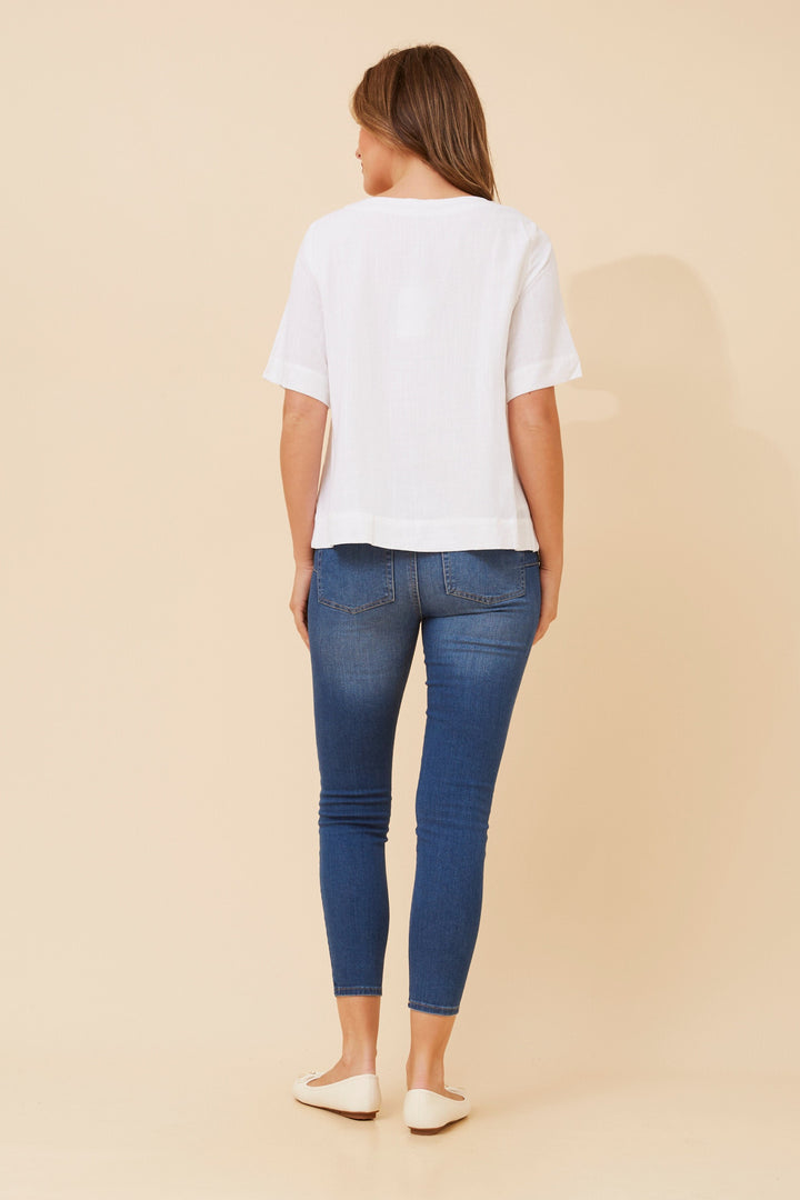 Woman wearing a white t-shirt and blue jeans on a beige background