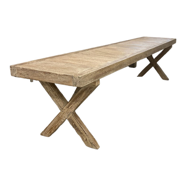 A long, handcrafted wooden bench with a white wash finish and a crossed-leg design, showcasing various wood tones.