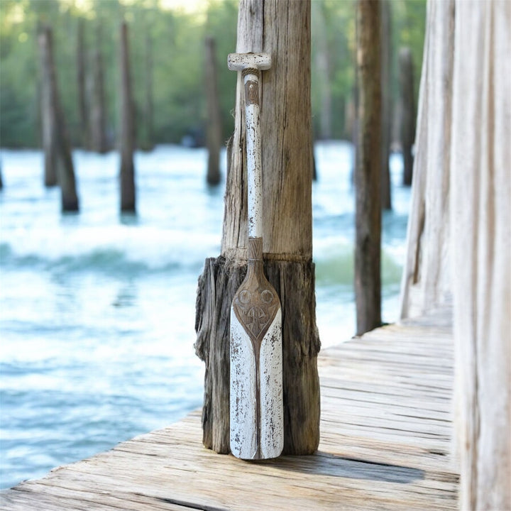 Decorative oar mounted on a wooden post by a body of water